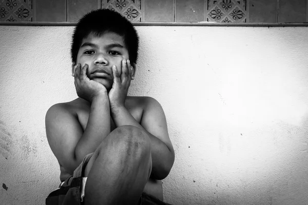 Gyerek koldus ül a konkrét falnak, fekete-fehér tonna — Stock Fotó