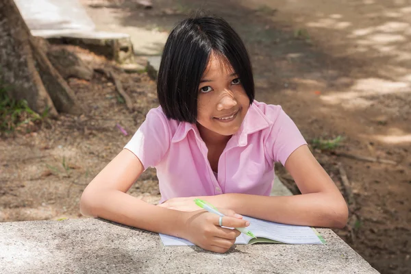 Bonito menina escrevendo livro no jardim — Fotografia de Stock