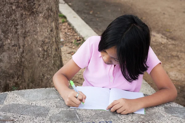 Mignonne fille écriture livre dans le jardin — Photo