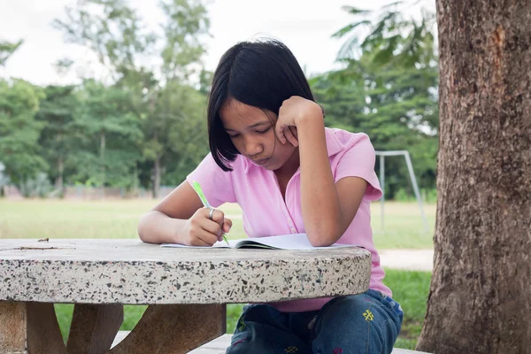 Leuk meisje schrijven boek in de tuin — Stockfoto