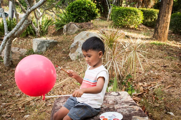 Piccolo ragazzo pittura su bolla rossa nel parco — Foto Stock