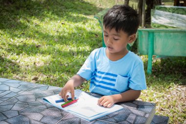 Sevimli küçük çocuk yapmak ödev sanat yeşil park