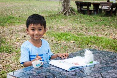 Sevimli küçük çocuk yapmak ödev sanat yeşil park