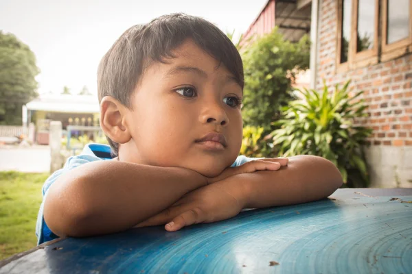 Niño triste y preocupado acostado en la mesa en el parque —  Fotos de Stock