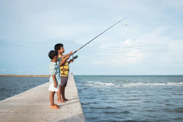 Mignon petit garçon pêche en mer — Photo