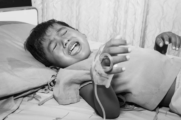 Petit garçon malade et pleurant sur le lit du patient, noir et blanc — Photo