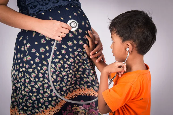 Lindo niño escuchar un estetoscopio vientre de su madre embarazada —  Fotos de Stock