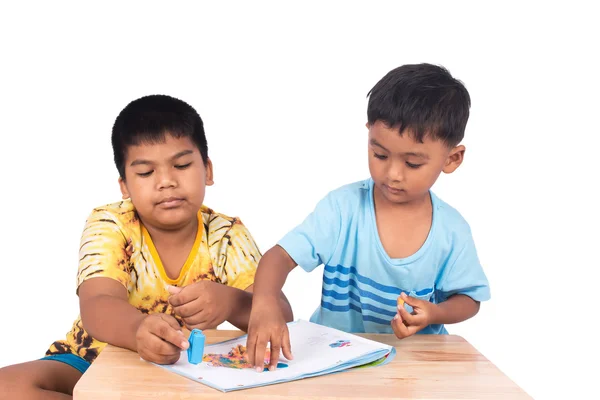 Два маленьких хлопчика грають глину на книзі на білому тлі — стокове фото