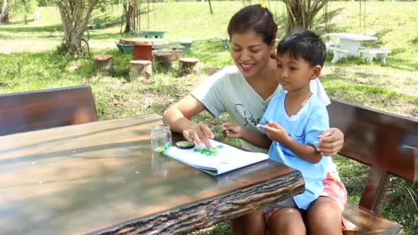 Madre aiutare suo figlio a fare i compiti nel parco — Video Stock