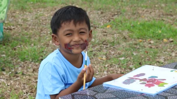 Bonito menino jogar pintura no rosto no parque verde — Vídeo de Stock