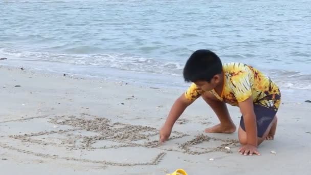 Schattige kleine jongen spelen en puttend uit zand op zee — Stockvideo