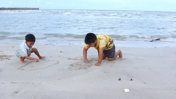 Söt liten pojke spela och ritning på sand till sjöss — Stockvideo