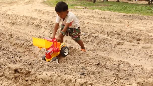 Petit garçon mignon jouant avec des jouets de voiture sur la plage — Video