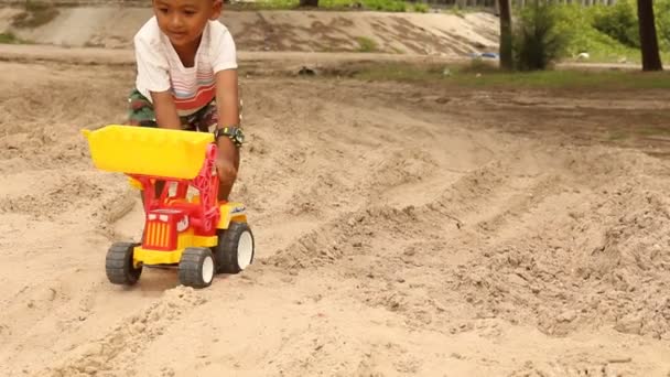 Χαριτωμένο μικρό αγόρι που παίζει με τα παιχνίδια αυτοκίνητο στην παραλία — Αρχείο Βίντεο