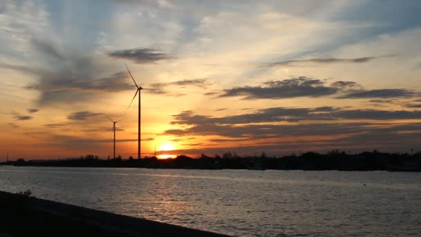 Zonsondergang van windturbine bij rivier achtergrond — Stockvideo