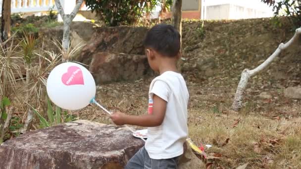 Милый маленький мальчик играет в воздушный шар и живопись — стоковое видео