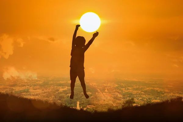 Silueta de niño feliz salto toque el sol, puesta del sol backgrou —  Fotos de Stock