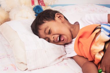 küçük bir Asyalı çocuk yatağa gülüyor