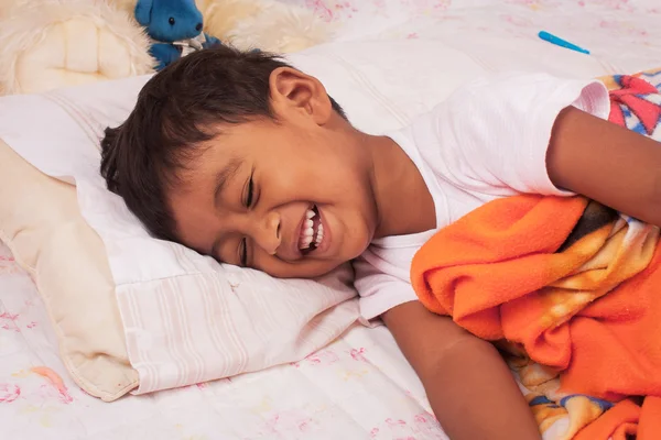 Um pouco asiático menino rindo no o cama — Fotografia de Stock