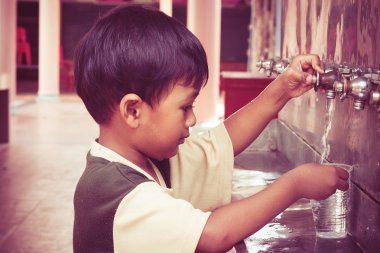 a little asian boy press the drinking water,vintage tone clipart