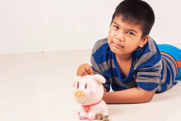 Bonito ásia menino poupança dinheiro no piggybank — Fotografia de Stock