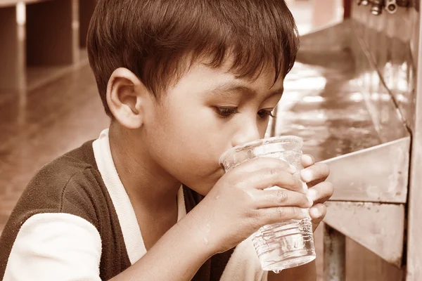 Маленький азіатський хлопчик п'є воду вінтажний тон — стокове фото