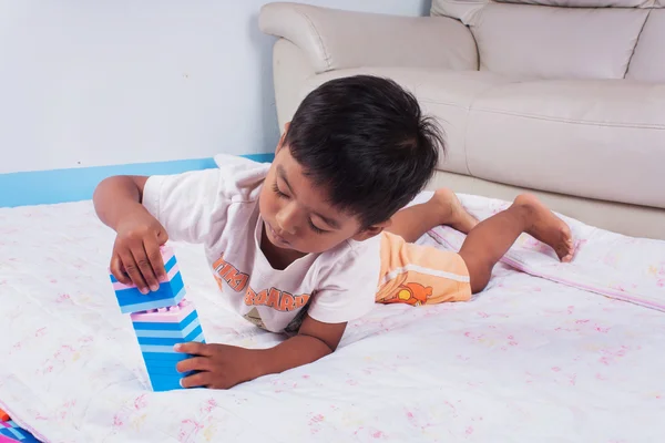 Um pouco asiático menino jogar com colorido plástico blocos no quarto — Fotografia de Stock