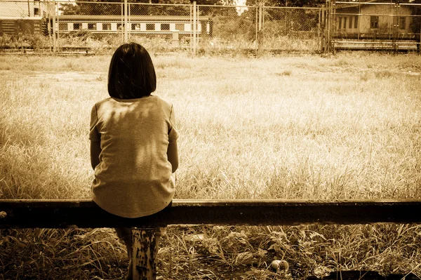 Triste asiático chica sentado solo cerca de ferrocarril estaciones, vintage ton — Foto de Stock