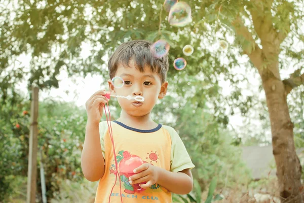 Little asian boy playing with bubble wand blowing soap bubbles,v