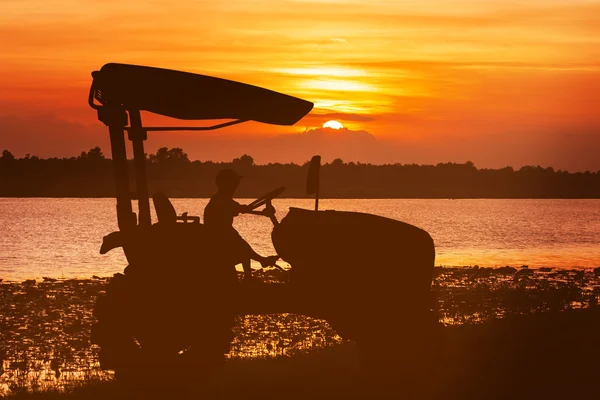 Asiatische kleine Junge Fahrer Traktor auf Fluss Sonnenuntergang Hintergrund — Stockfoto