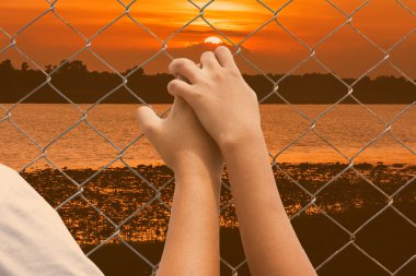 Hand girl in jail at river sunset background clipart