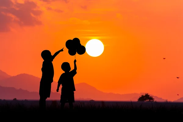 Силует азіатського маленького хлопчика вказує на сонце на заході сонця backgr — стокове фото