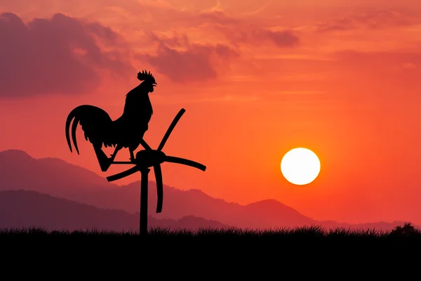 Roosters crow stand on a wind turbine. In the morning sunrise ba — Stock Photo, Image