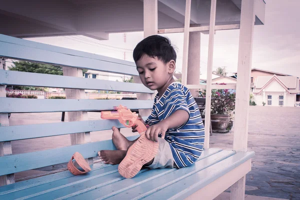Азиатский мальчик играет на стуле — стоковое фото