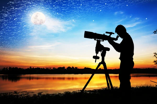 Silhouette di giovane che guarda attraverso un telescopio al completo — Foto Stock