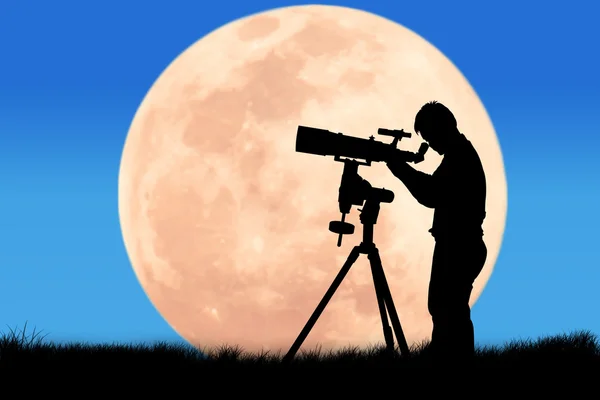 Silhouette di giovane uomo che guarda attraverso un telescopio — Foto Stock