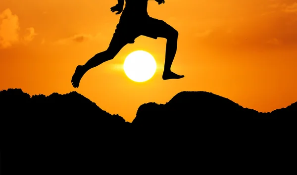 Silueta del joven saltando al atardecer amarillo de montaña ba —  Fotos de Stock