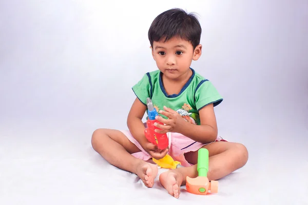 Bonito menino jogar ferramenta brinquedo de plástico no fundo branco — Fotografia de Stock
