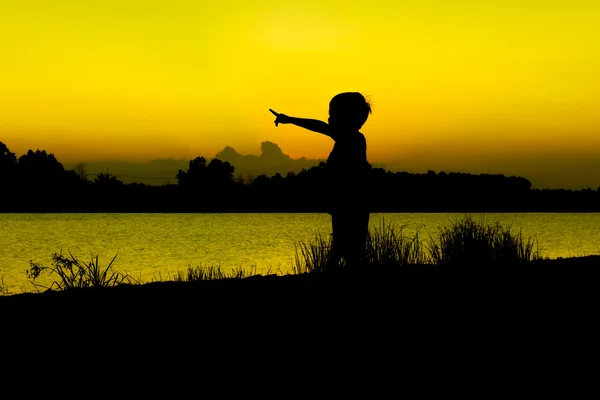 Niño pequeño jugar y señalar con el dedo el fondo del atardecer del río —  Fotos de Stock