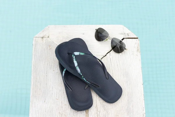 Infradito e occhiali da sole a bordo piscina blu — Foto Stock