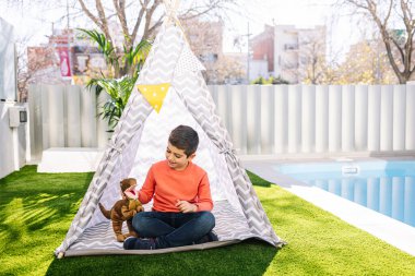 Küçük çocuk Kızılderili çadırında oynuyor.