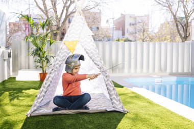 Küçük çocuk Kızılderili çadırında oynuyor.