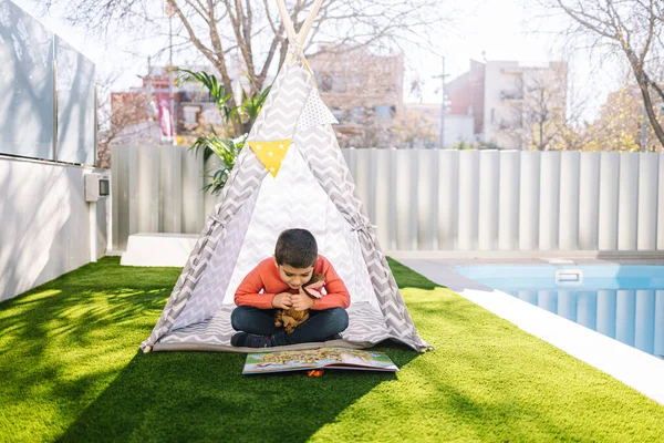 Küçük çocuk Kızılderili çadırında oynuyor.