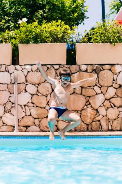 Küçük çocuk havuza atlıyor.