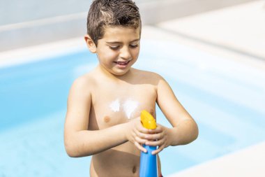 Küçük çocuk bir yaz günü güneş kremi sürüyor.