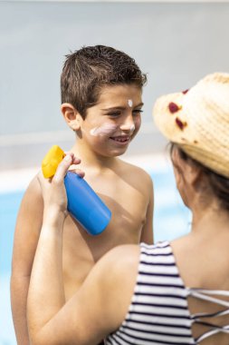 Anne bir yaz gününde oğluna güneş kremi sürüyor.