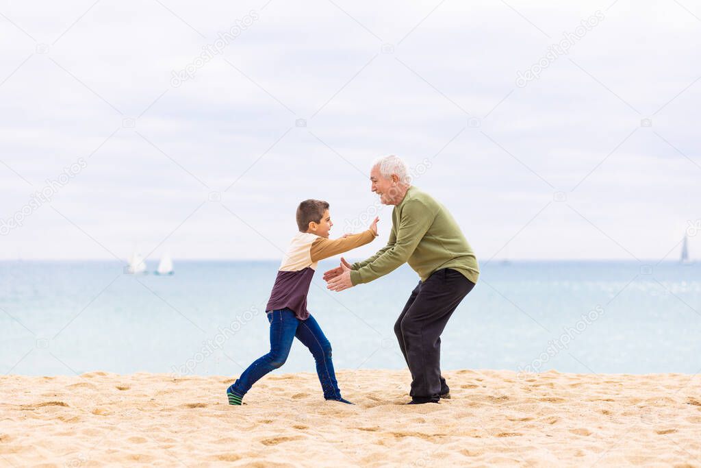 Happy boy running to hug his grandfather on the beach