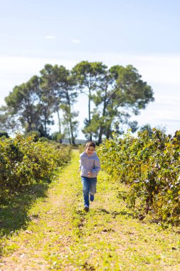 Küçük çocuk koşuyor, üzüm bağı fırlatıyor.