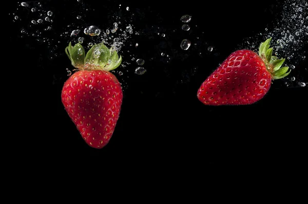 Erdbeeren planschen im Wasser — Stockfoto