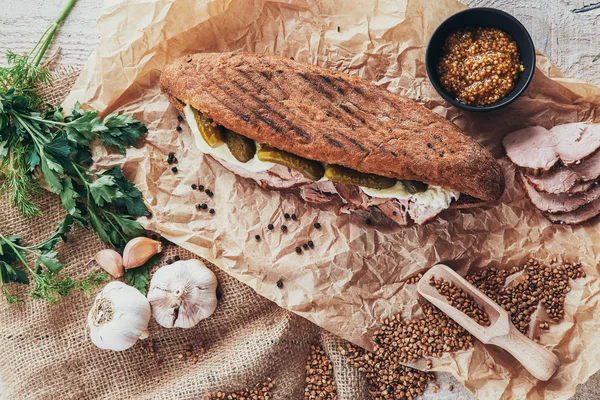 Rustic panini on wooden board with garlic, cucumber and ham — Stock Photo, Image